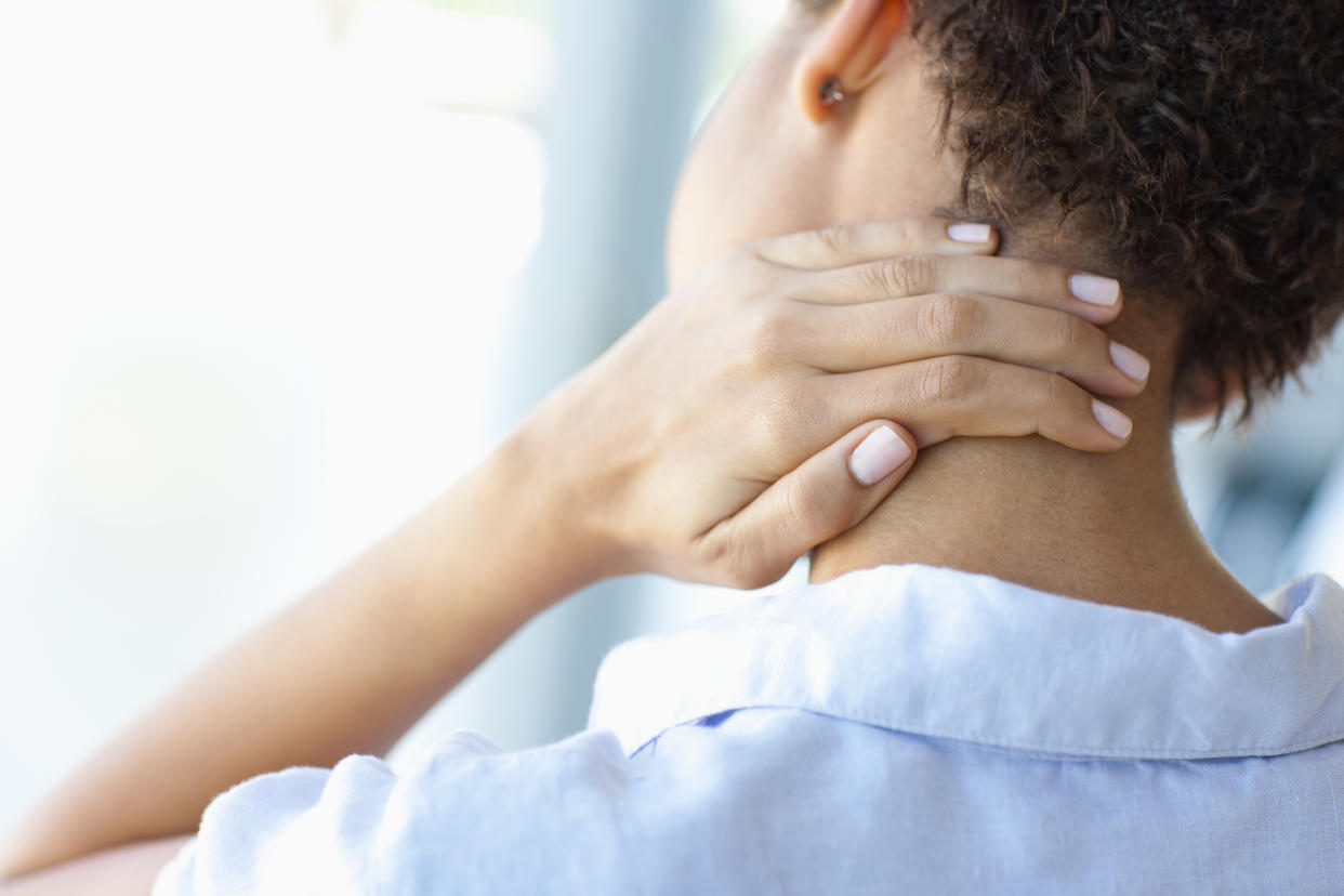 Amazon's $21 neck stretcher can help relieve neck and shoulder pain. (Getty Images) woman massages back of her neck