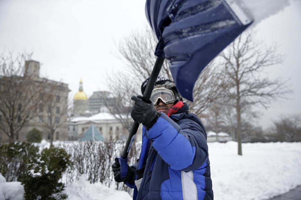 Marco Garcia, of Guatemala, shovels snow near the Statehouse in Tuesday, Feb. 18, 2014, in Trenton, N.J., after a quick-moving storm brought several inches of snow as well as rare "thundersnow" to parts of the winter-weary East Coast. (AP Photo/Mel Evans)