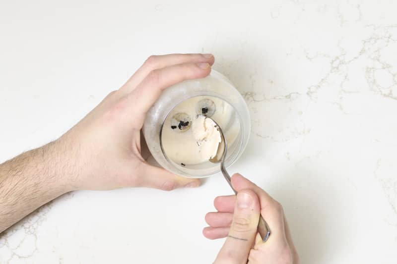 shot of someone scraping the remaining wax out of the used candle jar