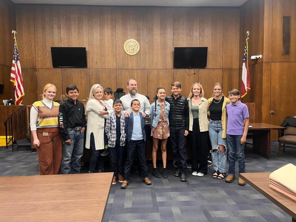 Angela and Elliott Turbeville pose in a Columbus courtroom with their seven adopted children and three biological children after the April 2023 hearing finalized the adoption of the seventh sibling.