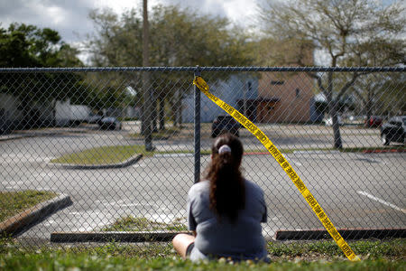 A woman mourns in front of the fence of the Marjory Stoneman Douglas High School, after the police security perimeter was removed, following a mass shooting in Parkland, Florida, U.S., February 18, 2018. REUTERS/Carlos Garcia Rawlins