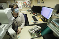 Dr. Desiree Marshall, director of Autopsy and After Death Services for University of Washington Medicine, uses a microscope to examine tissues from a person who died of COVID-19 related complications, as she works in her office, Tuesday, July 14, 2020, in Seattle. Autopsies reveal “what the virus is actually doing” inside patient’s bodies, says Marshall. (AP Photo/Ted S. Warren)