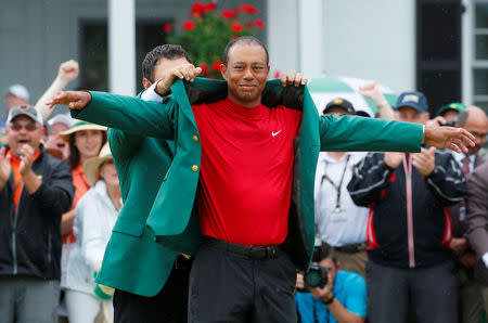 Golf - Masters - Augusta National Golf Club - Augusta, Georgia, U.S. - April 14, 2019 - Patrick Reed places the green jacket on Tiger Woods of the U.S. after Woods won the 2019 Masters. REUTERS/Brian Snyder