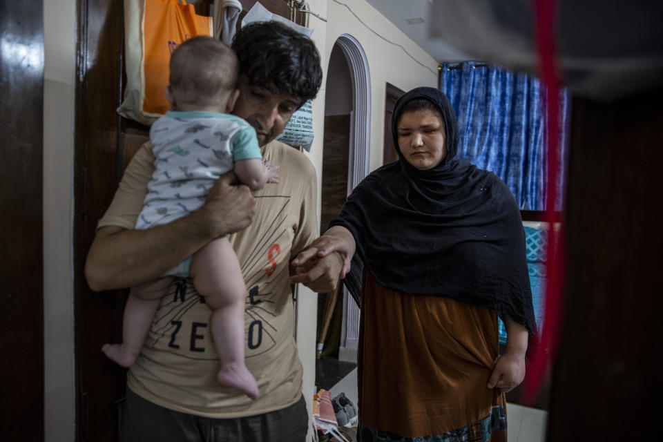 Mohammad Nabi holds his seven-month-old daughter Bahar as he helps his wife, a former Afghan policewoman Khatera Hashmi inside a rented accommodation in New Delhi, India, on Aug. 13, 2021. When the Taliban shot policewoman Khatira Hashmi and gouged out her eyes, she knew Afghanistan was no longer safe. Along with her husband, she fled to India last year. She was shot multiple times on her way home from work last October in the capital of Ghazni province, south of Kabul. As she slumped over, one of the attackers grabbed her by the hair, pulled a knife and gouged out her eyes. (AP Photo/Altaf Qadri)