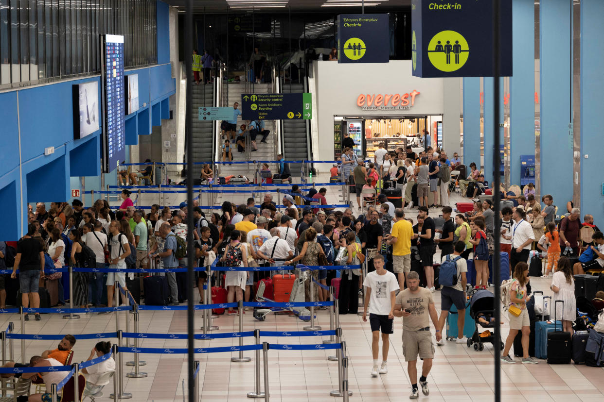 Tourists line up at check-in counters as they wait for departing planes at the airport, after being evacuated following a wildfire on the island of Rhodes, Greece, July 24, 2023. REUTERS/Nicolas Economou