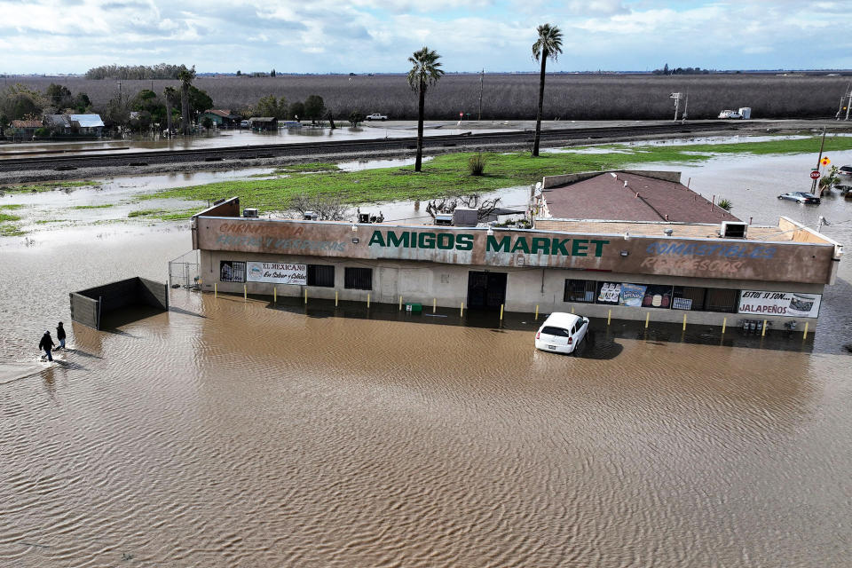 Residents navigate through flood waters on Jan. 10, 2023, in Planada, California.