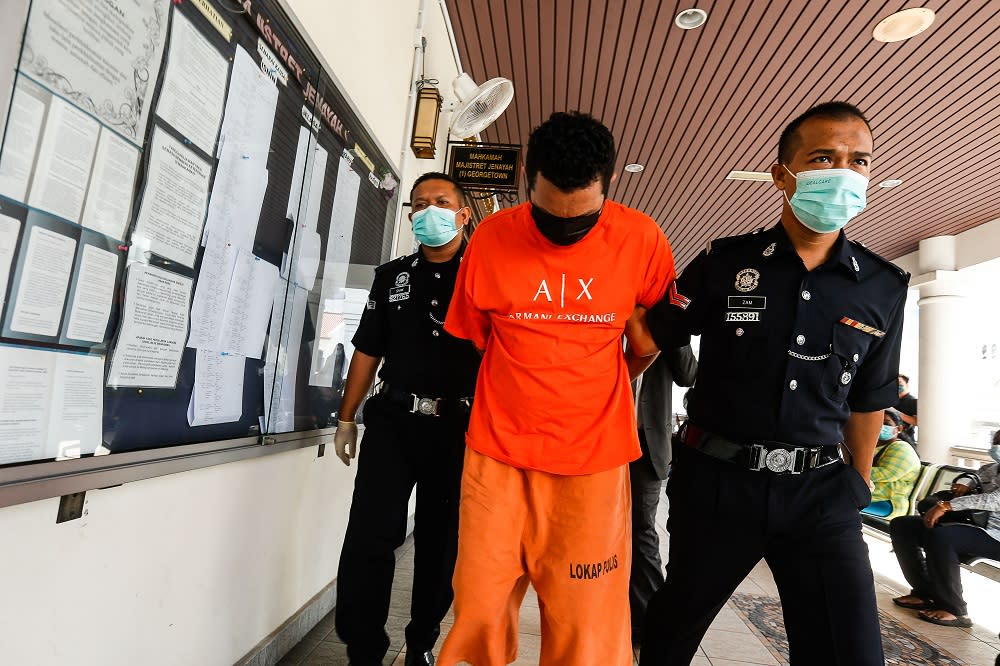 Mohd Arafat Taufik is escorted by policemen at the Magistrate’s Court in George Town April 23, 2021. ― Picture by Sayuti Zainudin