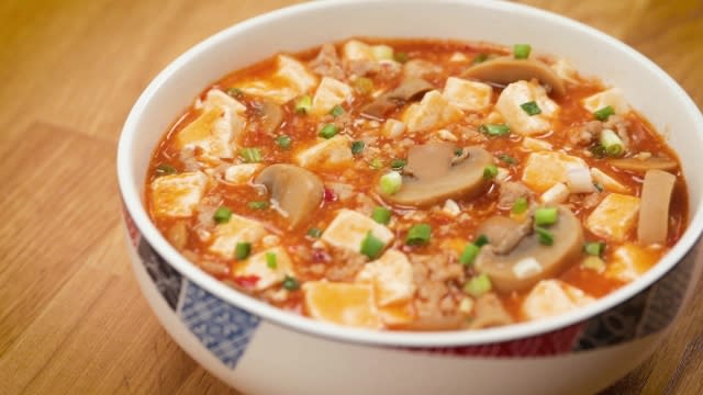 mapo tofu with canned mushrooms garnished with spring onions in a white bowl