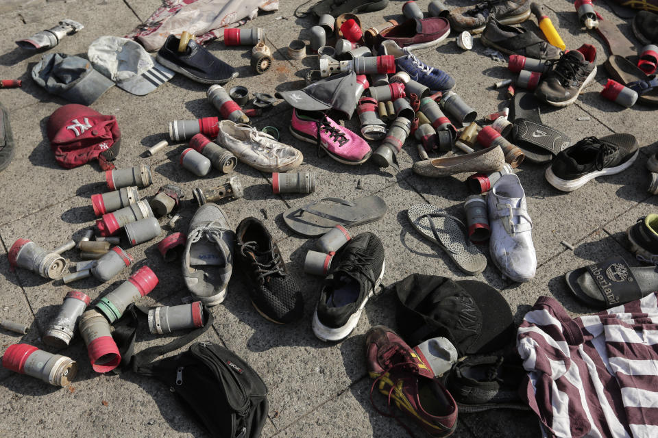 Tear gas canisters used by the Lebanese riot police and shoes left by protesters collected on the street in the aftermath of a protest against the Lebanese government in Beirut, Lebanon, Saturday, Oct. 19, 2019. The blaze of protests was unleashed a day earlier when the government announced a slate of new proposed taxes, including a $6 monthly fee for using Whatsapp voice calls. Arabic on the wall reads "Revolution, left, Leave,". (AP Photo/Hassan Ammar)