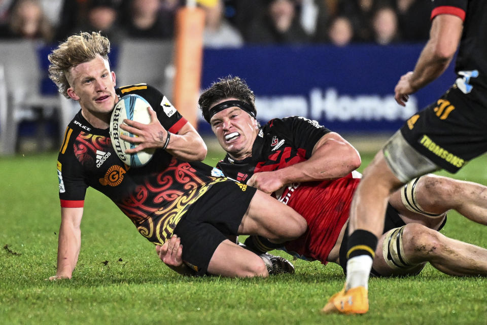 Damian McKenzie, left, of the Chiefs tackled by Scott Barrett of the Crusaders during the Super Rugby Pacific final between the Chiefs and the Crusaders in Hamilton, New Zealand, Saturday, June 24, 2023. (Andrew Cornaga/Photosport via AP)