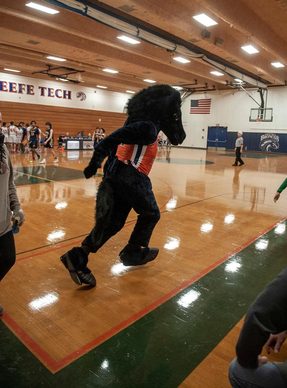 The Keefe Tech mascot, Billy the Bronco, senior TJ Nickerson, racesa across the court in the basketball home opener against Minuteman Tech, Dec. 14, 2023.