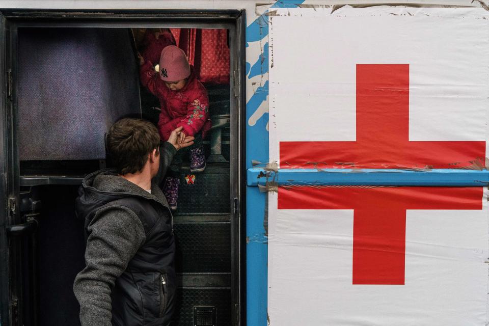 A child is helped off a bus at the registration center in Zaporizhzhia.