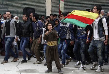 A Kurdish boy waves a Kurdish flag during celebrations after it was reported that Kurdish forces took control of the Syrian town of Kobani, in Sheikh Maksoud neighborhood of Aleppo January 27, 2015. REUTERS/Hosam Katan