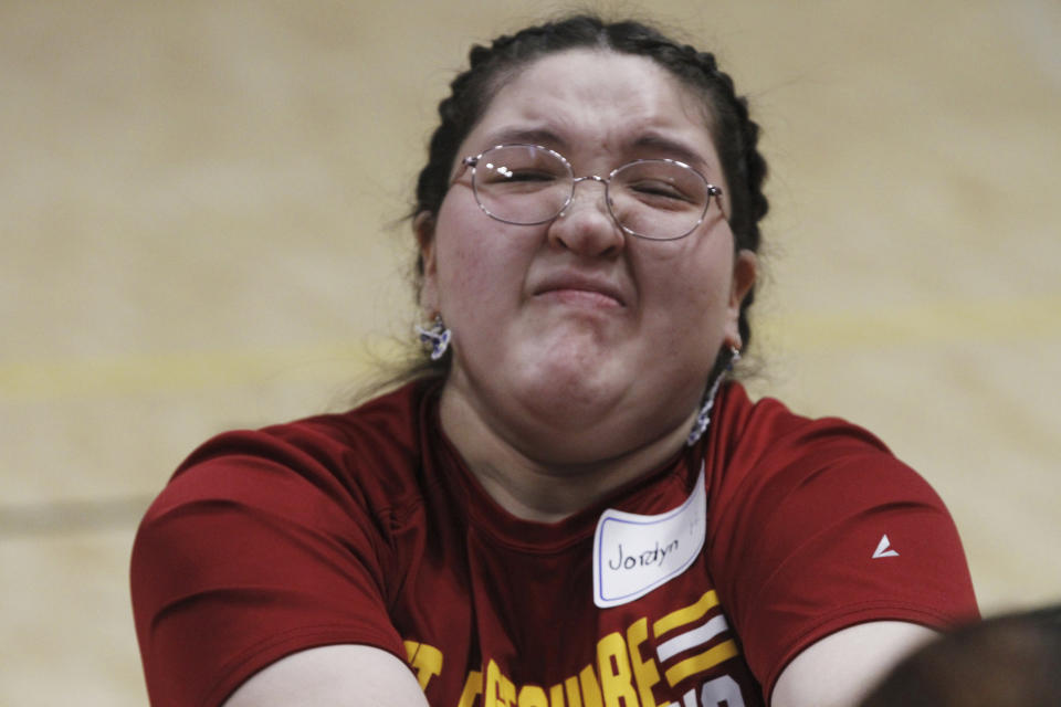 Jordyn Hoffman, of Mount Edgecumbe High School in Sitka, Alaska, scrunches her face as she participates in the Eskimo stick pull at the Native Youth Olympics, Friday, April 26, 2024, in Anchorage, Alaska. The Native Youth Olympics is a statewide competition that attracts hundreds of Alaska Native athletes each year and pays tribute to the skills and techniques used by their ancestors to survive in the harsh polar climate. (AP Photo/Mark Thiessen)