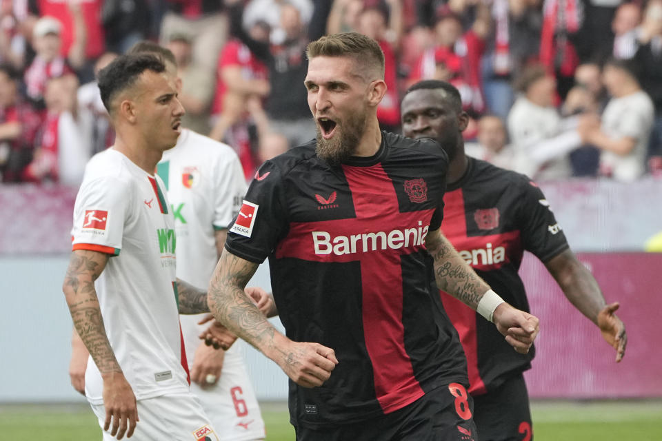 Leverkusen's Robert Andrich, centre, celebrates after scoring his side's second goal during the German Bundesliga soccer match between Bayer Leverkusen and FC Augsburg at the BayArena in Leverkusen, Germany, Saturday, May 18, 2024. (AP Photo/Martin Meissner)