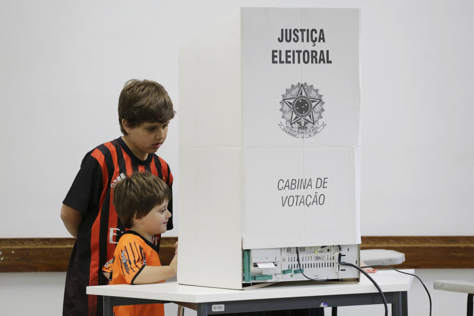 Boys accompany their mom as she votes in the general election in Sao Paulo, Brazil, Sunday, Oct. 7, 2018. Brazilians have started trickling to voting booths to choose leaders in an election marked by intense anger at the ruling class following years of political and economic turmoil. (AP Photo/Nelson Antoine)