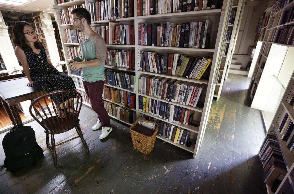 Brown University students Nicha Ratana-Apiromyakij, left, and Nick Melachrinos talk while visiting the stacks at the Providence Athenaeum, in Providence, R.I. on Monday, July 15, 2013. With roots dating back to 1753, the private library is one of the oldest in the country. It is housed in a Greek Revival-style granite building that neighbors Brown University and the Rhode Island School of Design. (AP Photo/Steven Senne)