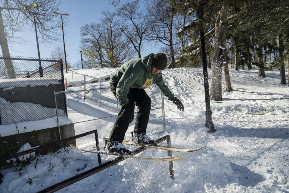 Ollie Wright hits a rail off of a home-made snow kicker built by friends, enjoying the aftermath of two days of lake-effect snow, near Hoyt Lake in Buffalo, N.Y., Sunday, Nov. 20, 2022. Just south of Buffalo, towns are still working to dig out from the lake-effect storm, but in parts of the city, everyday life is resuming. (Libby March/The Buffalo News via AP)