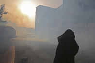 A Bahraini woman runs from tear gas in Sanabis, Bahrain, on the edge of the capital of Manama, Saturday, April 19, 2014. Clashes between anti-government protesters and police erupted during a march in the village over a dispute between relatives and authorities about the official cause of death for a 27-year-old man who died Thursday of injuries sustained in earlier clashes. Authorities in Bahrain say an apparent car bombing has killed two people and wounded one west of the capital, Manama. (AP Photo/Hasan Jamali)