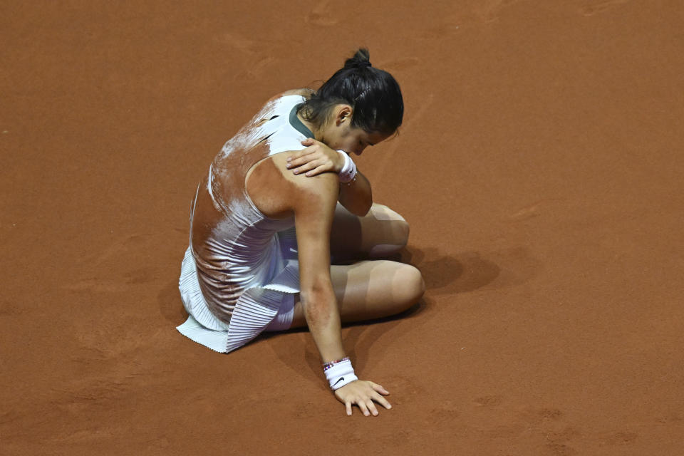 Britain's Emma Raducanu lies on the court after falling as she plays Poland's Iga Swiatek during her quarterfinals tennis match at the WTA Tour in Stuttgart, Germany, Friday April 19, 2024. (Marijan Murat/dpa via AP)