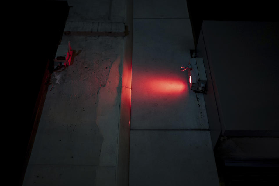 Light from an electric control box that the collective "On the Spot" uses to extinguish the lights on dozens of storefronts in Paris, Friday, July 29, 2022. (AP Photo/Lewis Joly)