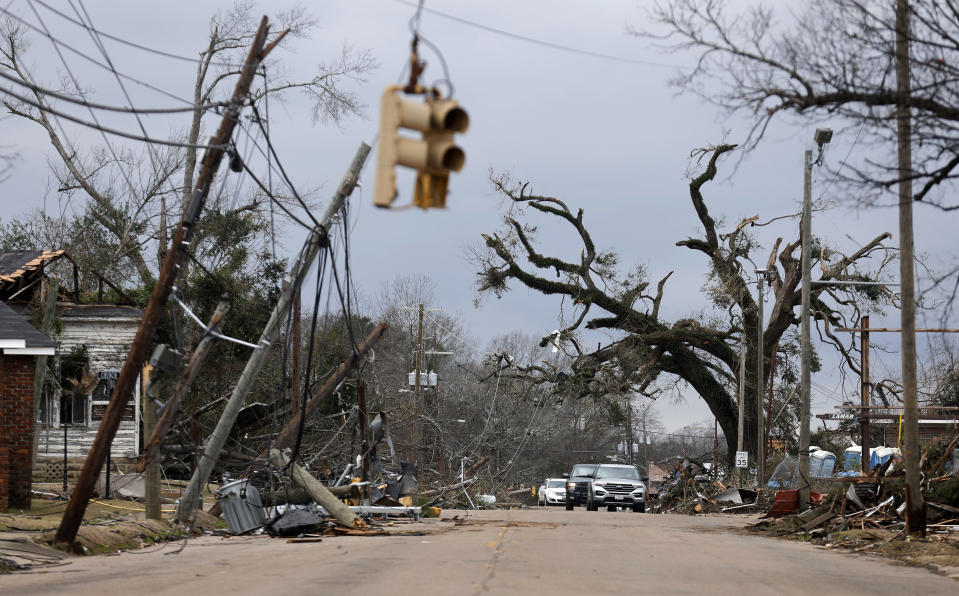 FILE - Cars navigate around downed trees and power lines on Chestnut Boulevard in Selma, Ala., on Jan. 13, 2023, after a tornado passed through the area the day before. President Joe Biden will travel to Alabama on Sunday, March 5, 2023, to mark the 58th anniversary of a landmark event of the civil rights movement. The visit comes as the city that served as a crucible of the civil rights movement is fighting to recover from a January tornado. (AP Photo/Stew Milne, File)