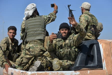 Members of Syrian National Army, known as Free Syrian Army, wave as they drive to cross into Syria near the Turkish border town of Ceylanpinar