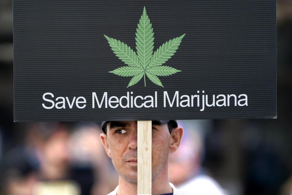 ARCHIVO - Un manifestante a favor de la marihuana para uso medicinal sostiene un cartel afuera del Centro Cívico de Augusta, donde se realiza una reunión de la legislatura estatal, el miércoles 28 de abril de 2021, en Augusta, Maine. (AP Foto/Robert F. Bukaty, archivo)