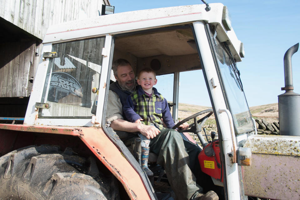 KIRKBY STEPHEN, UNITED KINGDOM - APRIL 15:  Sydney Owen, 2, sits in a tractor with his father Clive at Ravenseat, the farm of the Yorkshire Shepherdess Amanda Owen on April 15, 2014 near Kirkby Stephen, England. Amanda Owen runs a 2,000 acre working hill farm in Swaledale which is one of the remotest areas on the North Yorkshire Moors. Working to the rhythm of the seasons the farm has over 900 Swaledale sheep that are now entering the lambing season as well as cattle and horses.  (Photo by Ian Forsyth/Getty Images)