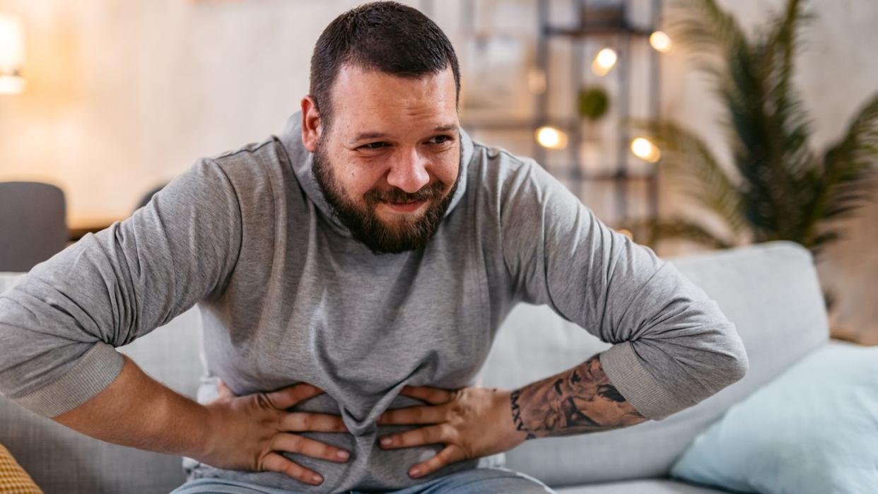 man with severe stomach pain sitting at home