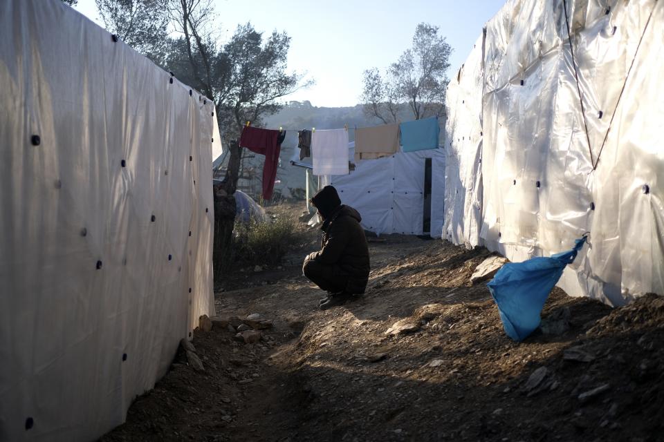 A migrants sits next to tents outside the Moria refugee camp on the northeastern Aegean island of Lesbos, Greece, on Wednesday, Jan. 22, 2020. Some businesses and public services on the eastern Aegean island are holding a 24-hour strike on Wednesday to protest the migration situation, with thousands of migrants and refugees are stranded in overcrowded camps in increasingly precarious conditions. (AP Photo/Aggelos Barai)