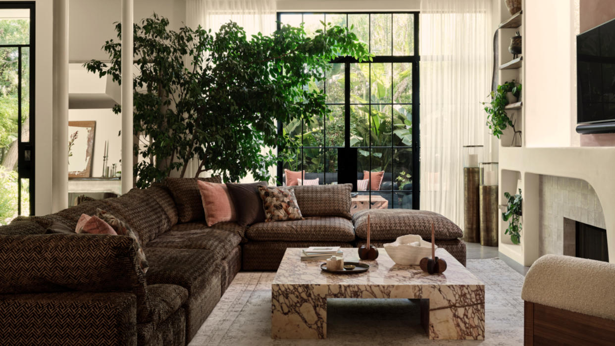  Living room with brown patterned corner sofa, marble coffee table and sculpted plaster fireplace. 