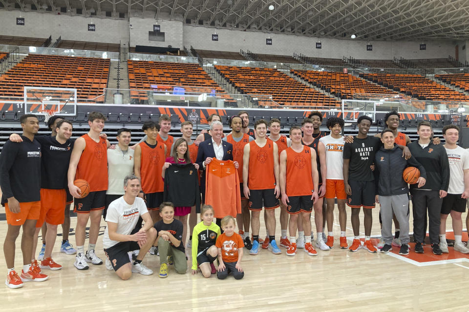 New Jersey governor Phil Murphy and his wife, Tammy, pose with members of the Princeton NCAA college basketball team in Princeton, N.J., Tuesday, March 21, 2022. Head coach Mitch Henderson kneels at front left. Princeton plays Creighton in a Sweet 16 college basketball game at the NCAA South Regional of the NCAA Tournament on Friday in Louisville, Ky. (AP Photo/Dan Gelston)