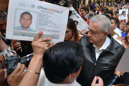 Mexico's President Andres Manuel Lopez Obrador talks with relatives of some of the many people registered as disappeared, as he arrives to give his address at the National Palace in Mexico City, Mexico March 24, 2019. Press Office Andres Manuel Lopez Obrador/Handout via REUTERS