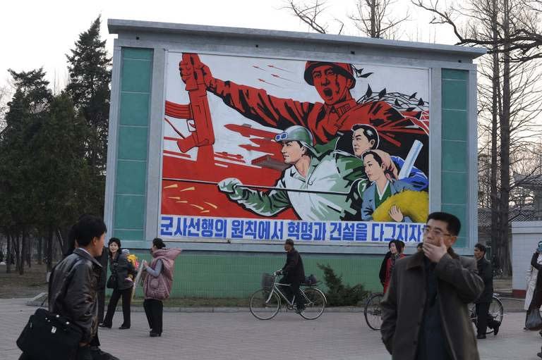 North Koreans stand in front of a political mural in Pyongyang, April 12, 2012. North Korea's shrill threats of nuclear war may seem overblown or absurd, but they are well tailored to a domestic audience raised on the constant fear of imminent US invasion, analysts say