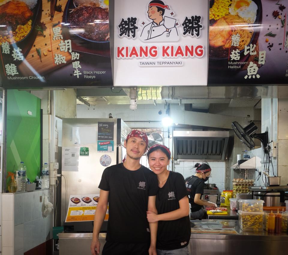 A couple poses in front of their stall