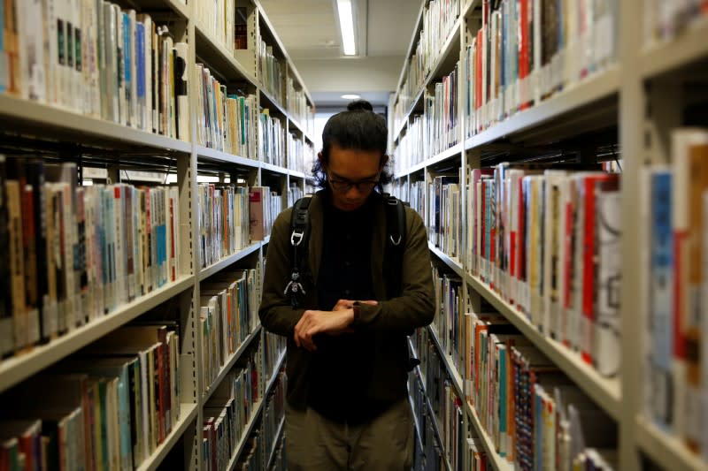 Derek Tai looks at his watch at a library at Chinese University of Hong Kong in Hong Kong