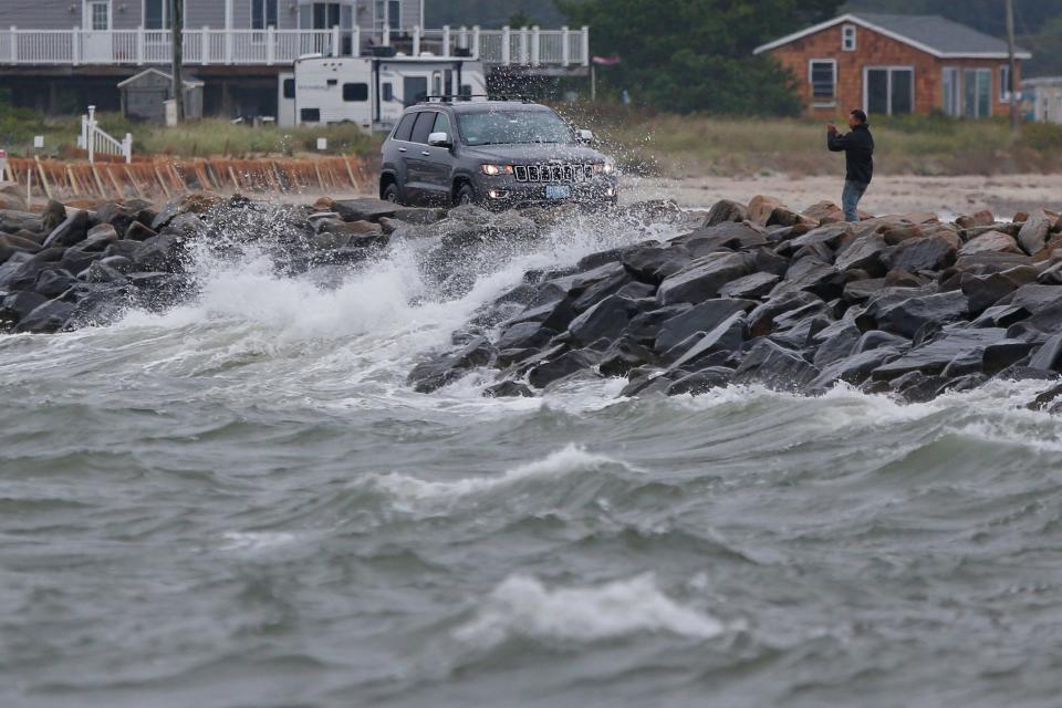 A man gets out of his car to take a photo of the waves being generated by Hurricane Lee from the Gooseberry Island causeway in Westport.