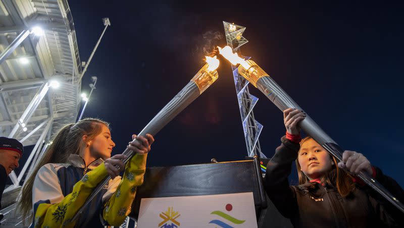 Gabrielle Harris, of Team Soldier Hollow Cross Country and Biathlon, and YiYi O’Brien, National Abilities Center Youth Adaptive Program athlete, combine Olympic torches from 2002 as the flame at Rice-Eccles Stadium in Salt Lake City is lit on Tuesday, Feb. 8, 2022, marking the 20th anniversary of the 2002 Olympic Games in Salt Lake City.