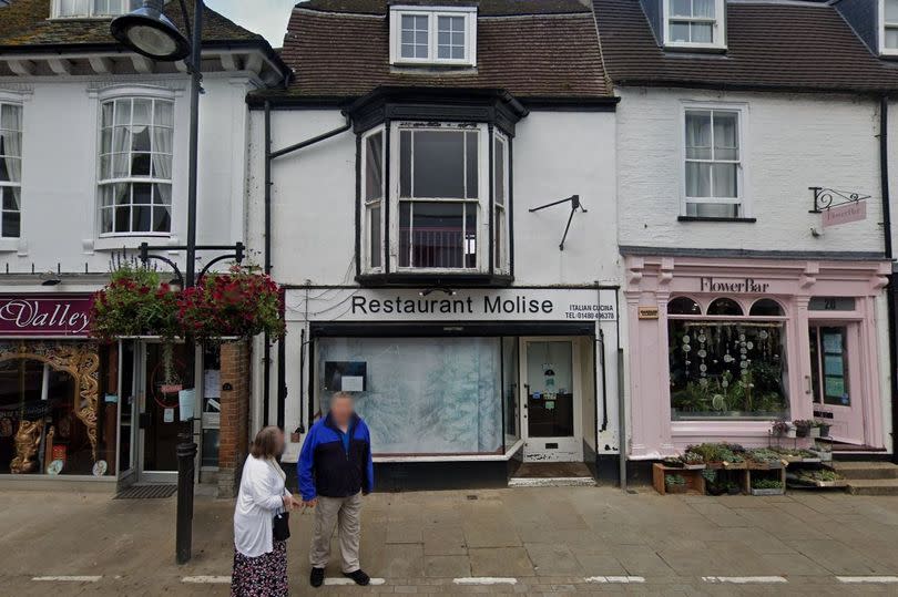 Exterior of two-storey white building, with restaurant on the ground floor.