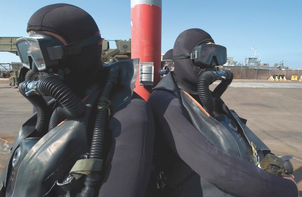 A tangle of neoprene, hoses, and rubber, BUD/S students await instructions in full scuba gear before scuba training.