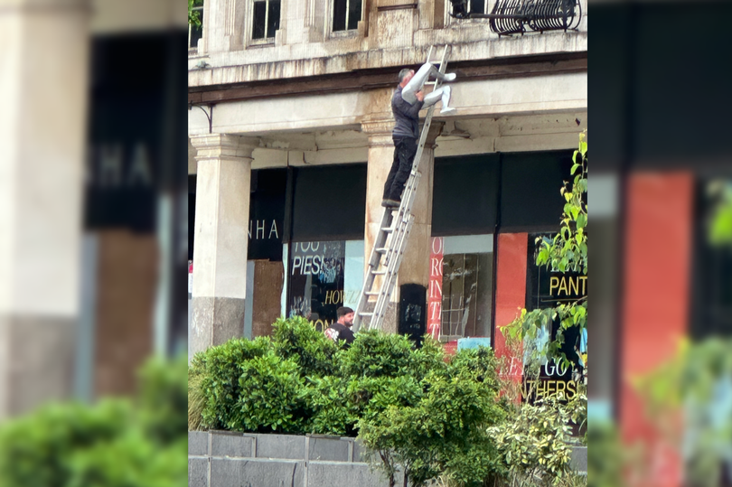A man on a ladder pictured removing the mannequin