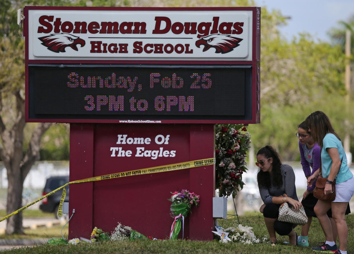 Mourners bring flowers as they pay tribute at a memorial for the victims of the shooting at Marjory Stoneman Douglas High School. (Getty)