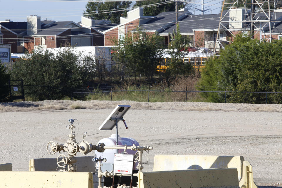 FILE - A natural gas well is juxtaposed with apartment buildings a few hundred feet away in Arlington, Texas, on Monday, Oct. 25, 2021. A new study finds that minority neighborhoods where residents were long denied home loans through a practice called redlining have twice as many oil and gas wells as mostly white neighborhoods. (AP Photo/Martha Irvine)