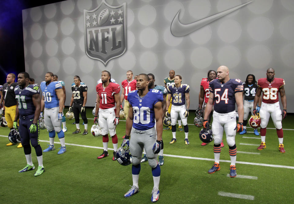 NFL players stand in their new uniforms during a presentation in New York, Tuesday, April 3, 2012. The league and Nike showed off the new look in grand style with a gridiron-styled fashion show at a Brooklyn film studio. (AP Photo/Seth Wenig)