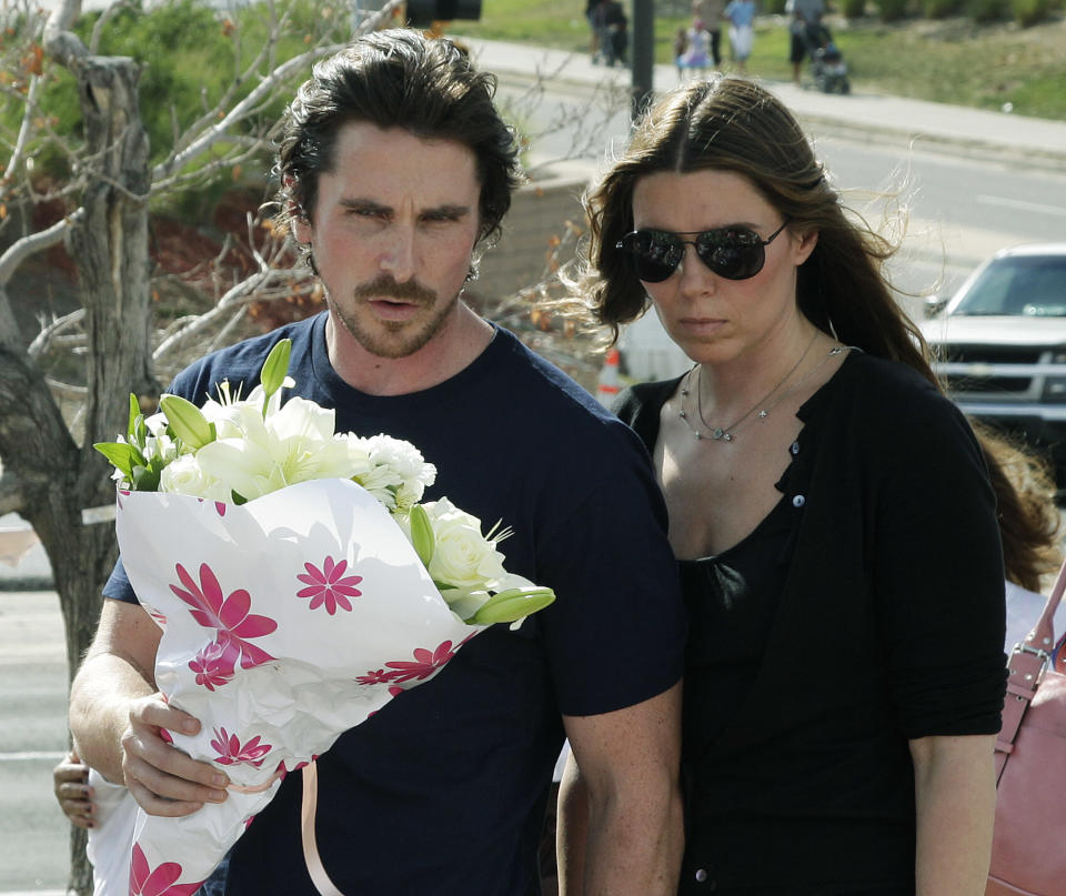 Actor Christian Bale and his wife Sibi Blazic carry flowers to place on a memorial to the victims of Friday's mass shooting, Tuesday, July 24, 2012, in Aurora, Colo. Twelve people were killed when a gunman opened fire during a late-night showing of the movie "The Dark Knight Rises," which stars Bale as Batman. (AP Photo/Ted S. Warren)