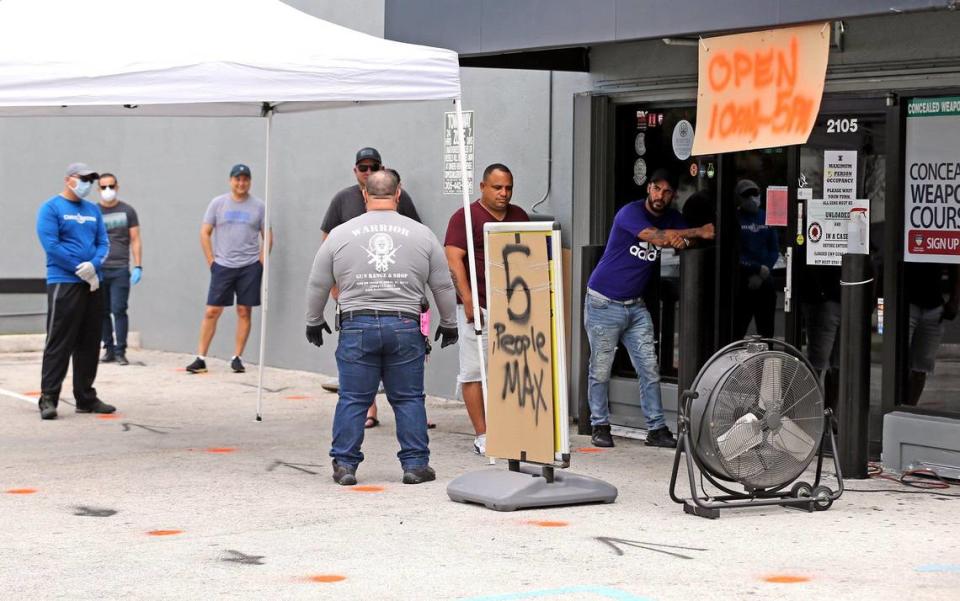 Customers line up six feet apart outside Warrior Gun Range and Gun Shop in Doral on Tuesday. Owner Charlie Berrane has seen soaring sales of guns and ammo as customers seek self-protection during the coronavirus pandemic. Stores are running out of inventory.