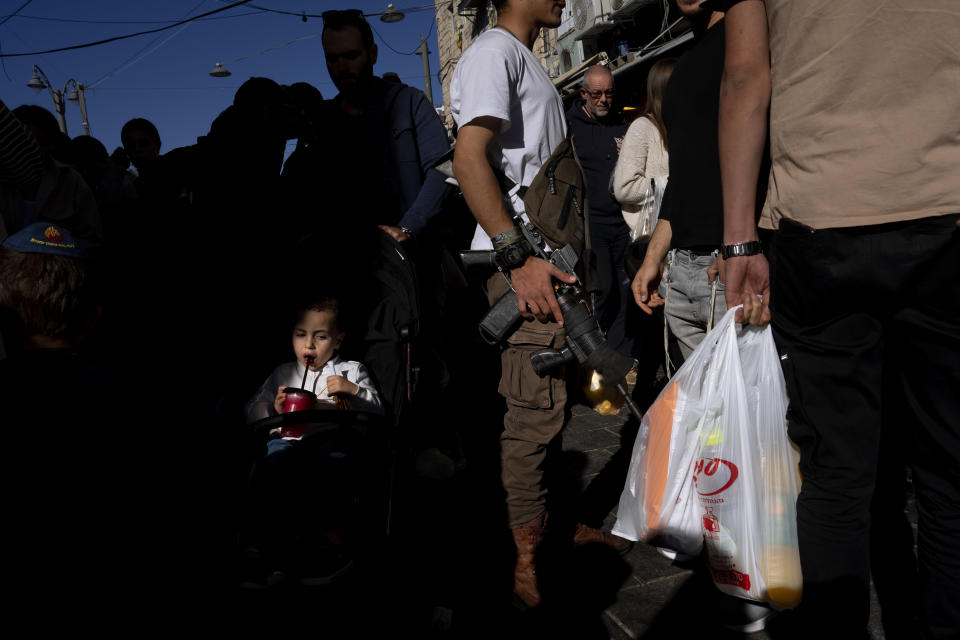 Un niño bebe de un vaso de plástico desechable mientras otras personas llevan productos en bolsas de plástico en el mercado de Mahane Yehuda en Jerusalén, el viernes 20 de enero de 2023. Los judíos ultraortodoxos, que tienen familias numerosas y emplean una gran cantidad de cubiertos y vajilla desechable, dicen que el impuesto a los plásticos de un solo uso les señalaba de forma injusta. (AP Foto/Oded Balilty)