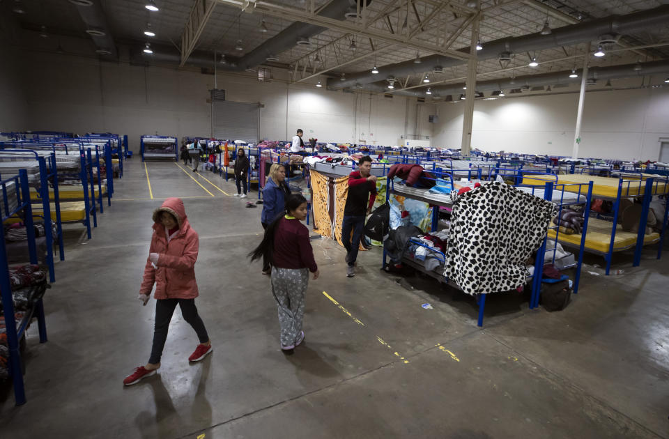 Migrants walk around bunk beds inside a government-run shelter in Ciudad Juarez, Mexico, on Sunday, Dec. 18, 2022. (AP Photo/Andres Leighton)