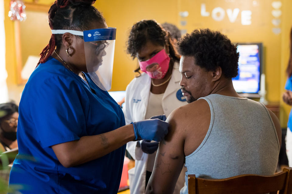 Keshawn Shaw looks at his arm where nurse Andretta Griffin, left, and Dr. Karen Smith, center, administered a Covid-19 vaccination at his grandmother Bessie Bratcher's home in Raeford, N.C. (Justin Kase Conder / for NBC News)